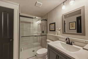 Bathroom featuring vanity, a stall shower, and a textured wall