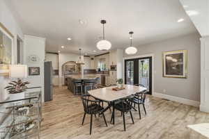 Dining room with recessed lighting, light wood-style flooring, arched walkways, and french doors