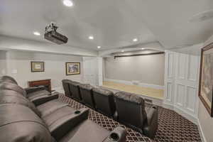 Carpeted home theater with recessed lighting and baseboards