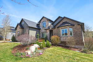 View of front of property with a front lawn, stone siding, and brick siding