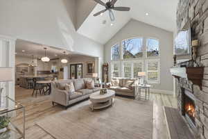 Living room featuring recessed lighting, a stone fireplace, light wood-style floors, ceiling fan, and vaulted ceiling
