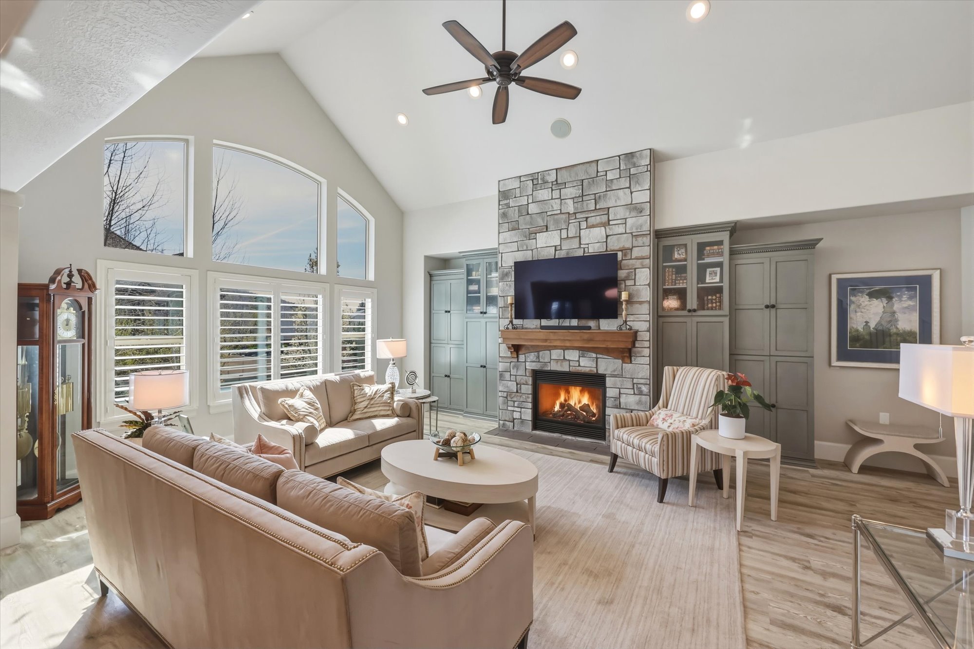 Living area featuring a fireplace, a high ceiling, light wood finished floors, a ceiling fan, and recessed lighting