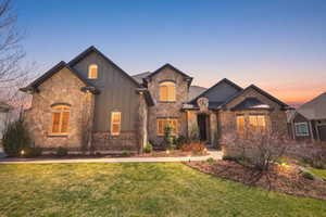 View of front of house with board and batten siding, a yard, and stone siding