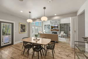 Dining space with light wood-style floors, a fireplace, and recessed lighting