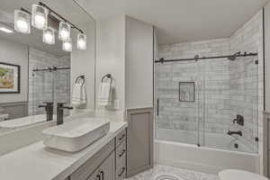 Full bath featuring vanity, bath / shower combo with glass door, and a wainscoted wall