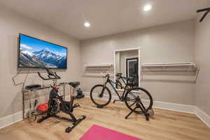 Exercise area with light wood finished floors and recessed lighting