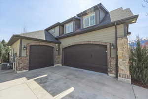 View of front of house with driveway, a shingled roof, and a garage