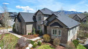 View of front facade with brick siding, stone siding, and a shingled roof