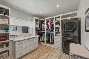Walk in closet featuring stacked washer and dryer and light wood-type flooring