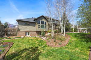 Back of house featuring a yard, brick siding, and board and batten siding