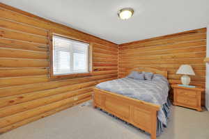 Bedroom with log walls and carpet