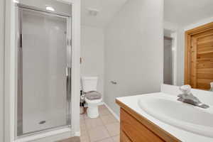 Full bath with a shower stall, vanity, a textured wall, and light tile patterned flooring