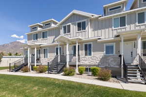 View of front of house with stone siding, board and batten siding, a mountain view, and a front lawn
