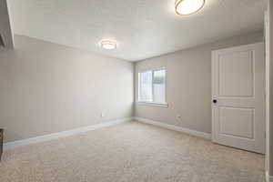 Empty room with a textured ceiling and light carpet