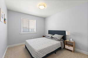 Bedroom with light colored carpet and a textured ceiling