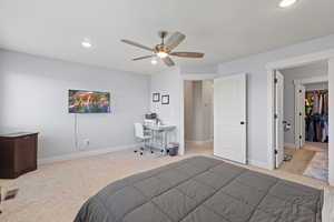 Bedroom featuring light colored carpet, recessed lighting, ceiling fan, an office area, and a walk in closet