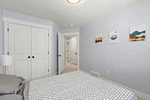 Bedroom with a closet, light carpet, and a textured ceiling