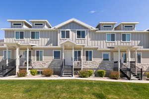 View of front of property featuring stone siding, board and batten siding, a front yard, and covered porch