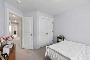 Bedroom with light carpet, a closet, and a textured ceiling