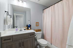Full bath with vanity, shower / tub combo with curtain, and a textured ceiling