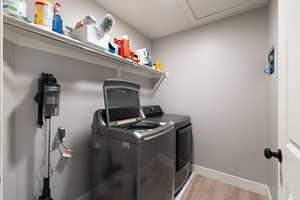 Laundry room with washer and dryer and light wood-type flooring