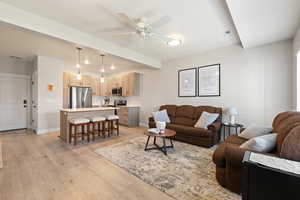 Living area featuring ceiling fan, light wood finished floors, and beamed ceiling
