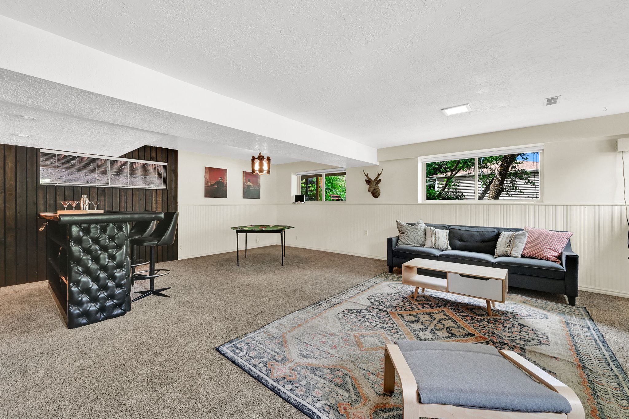Spacious lower-level family room featuring a built-in bar with a tufted front,