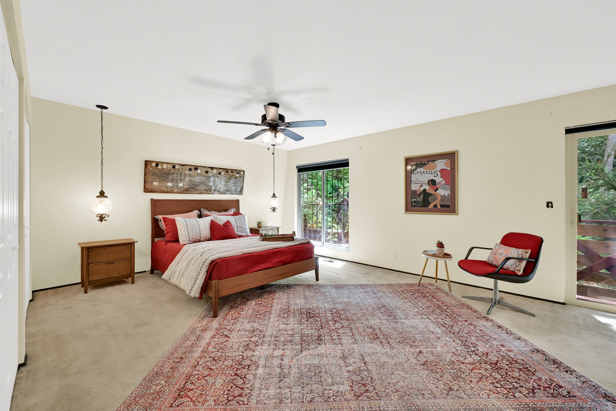 Huge primary bedroom with vintage lighting and slider to deck