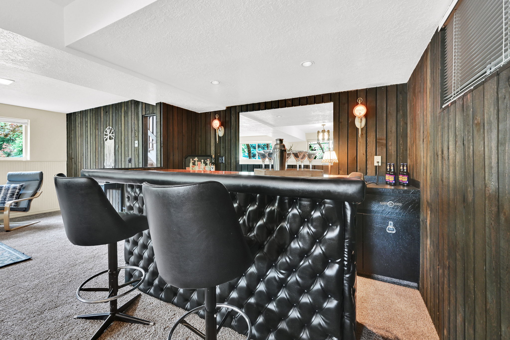 Built-in, retro wet bar with tufted upholstery, integrated mirror, and wood panelling