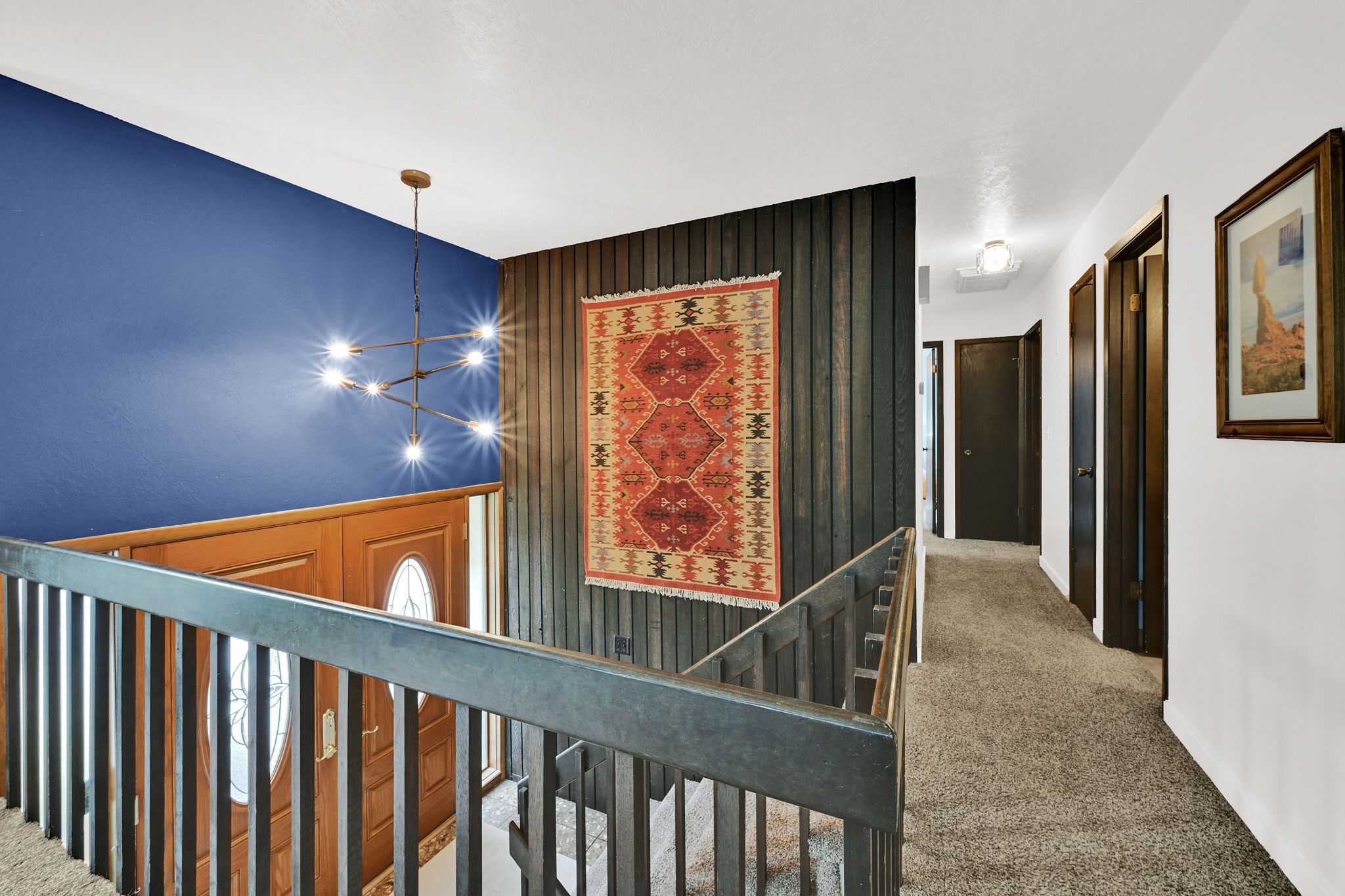 Entryway with a contemporary chandelier, a prominent blue accent wall, and wood paneling