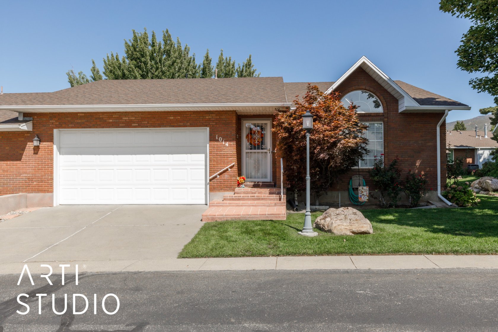 Single story home featuring a garage, driveway, brick siding, and a shingled roof