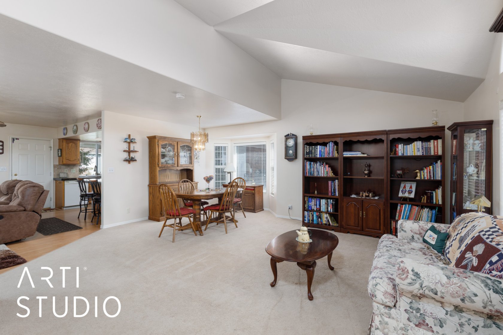 Living area with light carpet, vaulted ceiling, and hanging lights