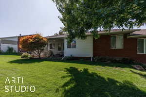 Rear view of house featuring a lawn, a patio area, and brick siding
