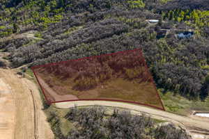 Aerial view of property and surrounding area featuring property parcel outlined and a forest