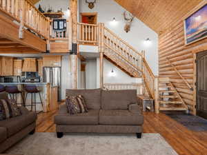 Living area with a vaulted wooden ceiling, rustic walls, and dark wood-style floors