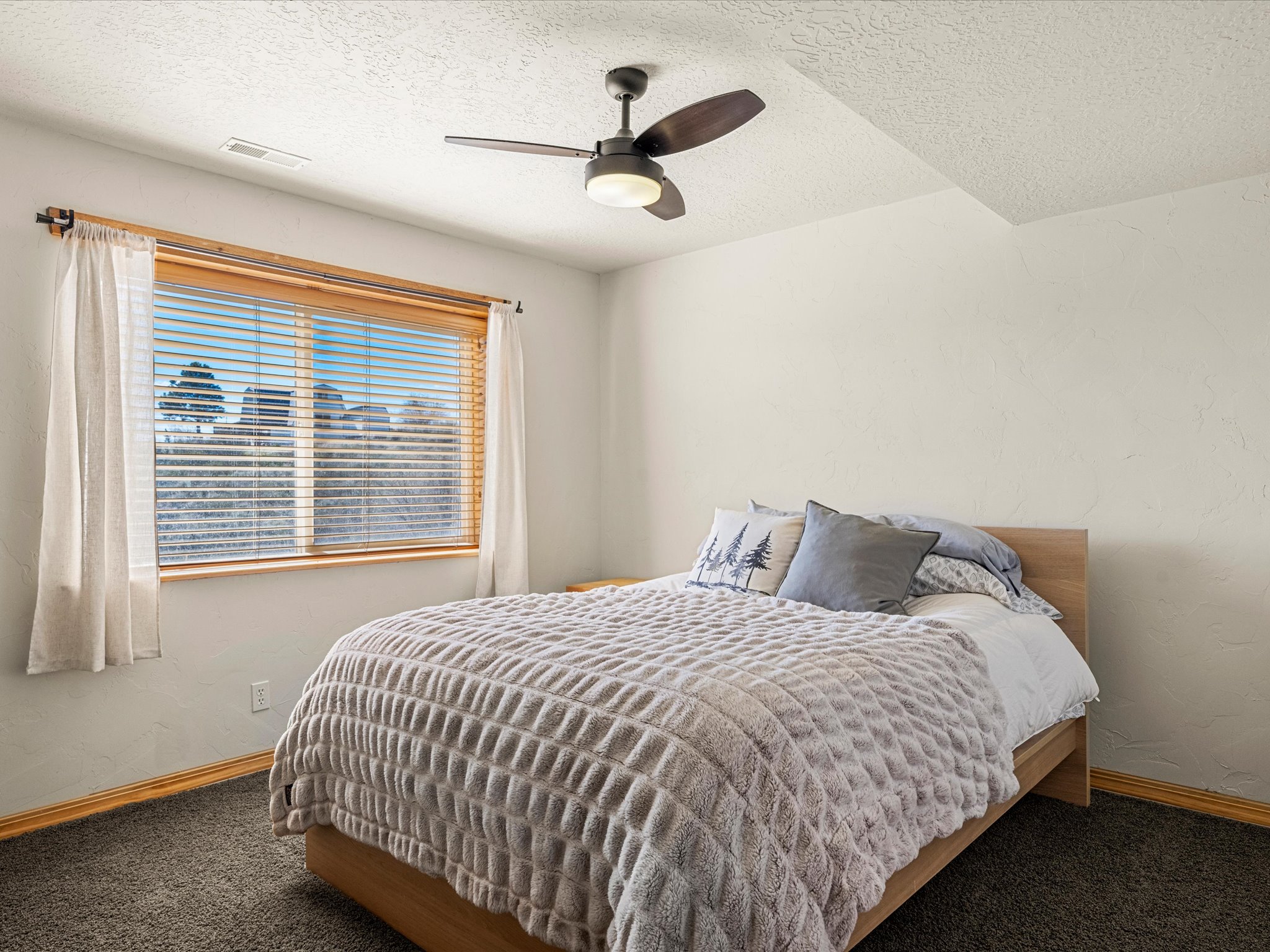 Bedroom with a ceiling fan, a textured ceiling, carpet flooring, and a textured wall