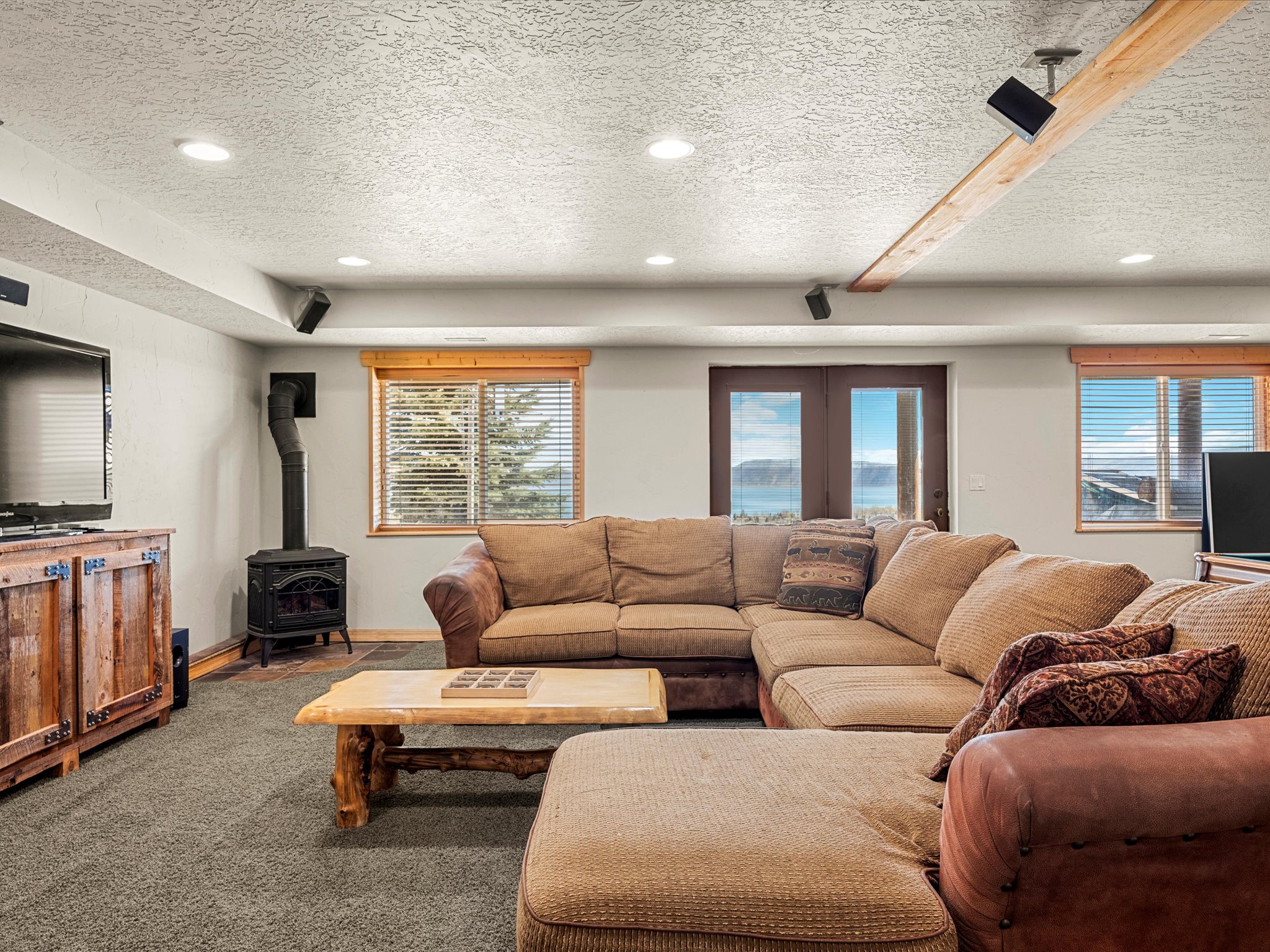 Living room with a wood stove, a textured ceiling, carpet, recessed lighting, and french doors