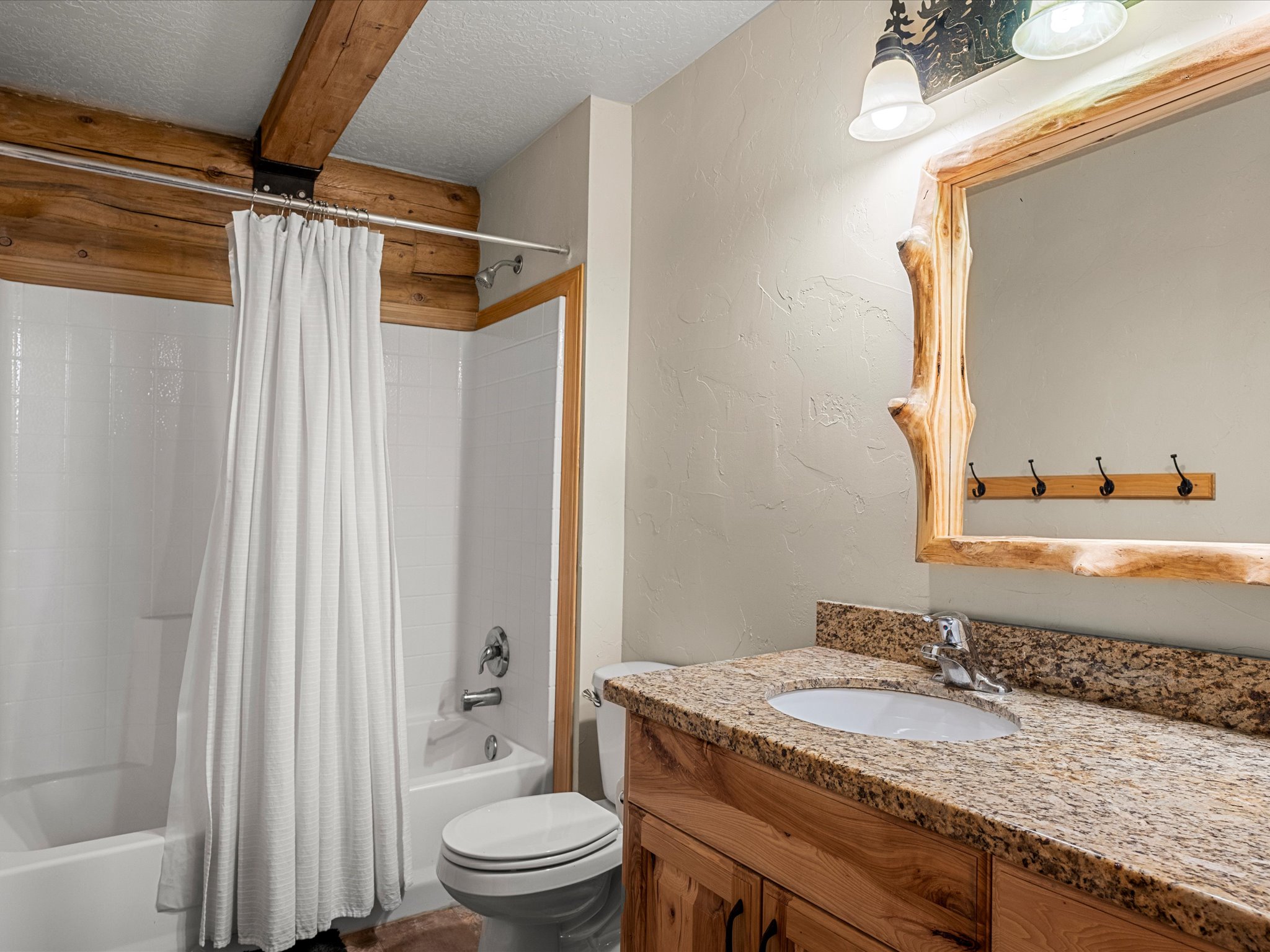 Full bath featuring a textured wall, a textured ceiling, vanity, and shower / tub combo with curtain