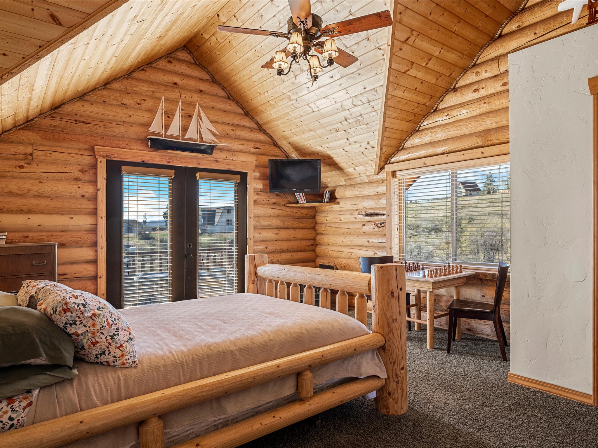 Bedroom featuring multiple windows, rustic walls, wooden ceiling, carpet floors, and french doors