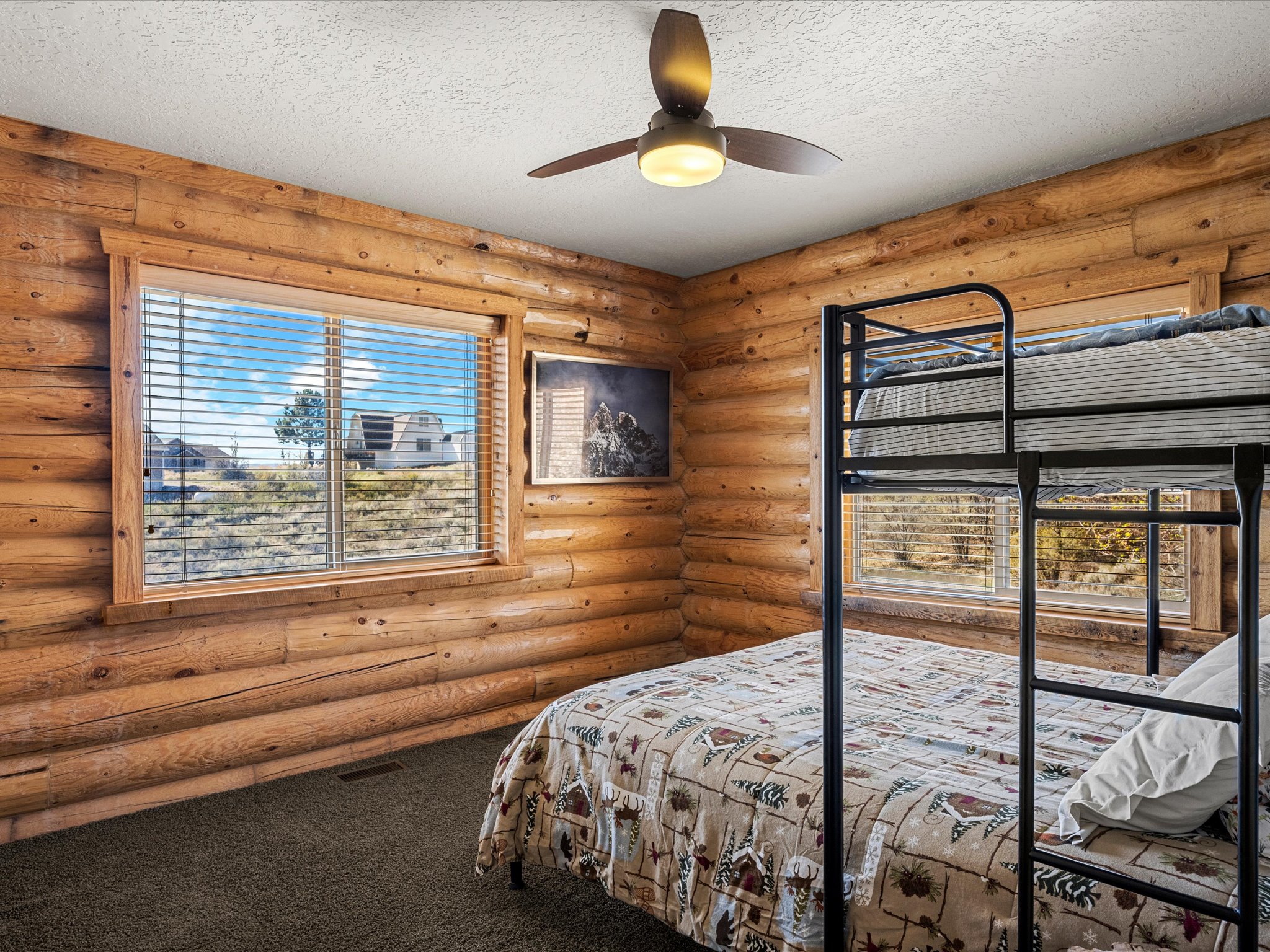 Bedroom featuring dark colored carpet, a textured ceiling, rustic walls, and a ceiling fan