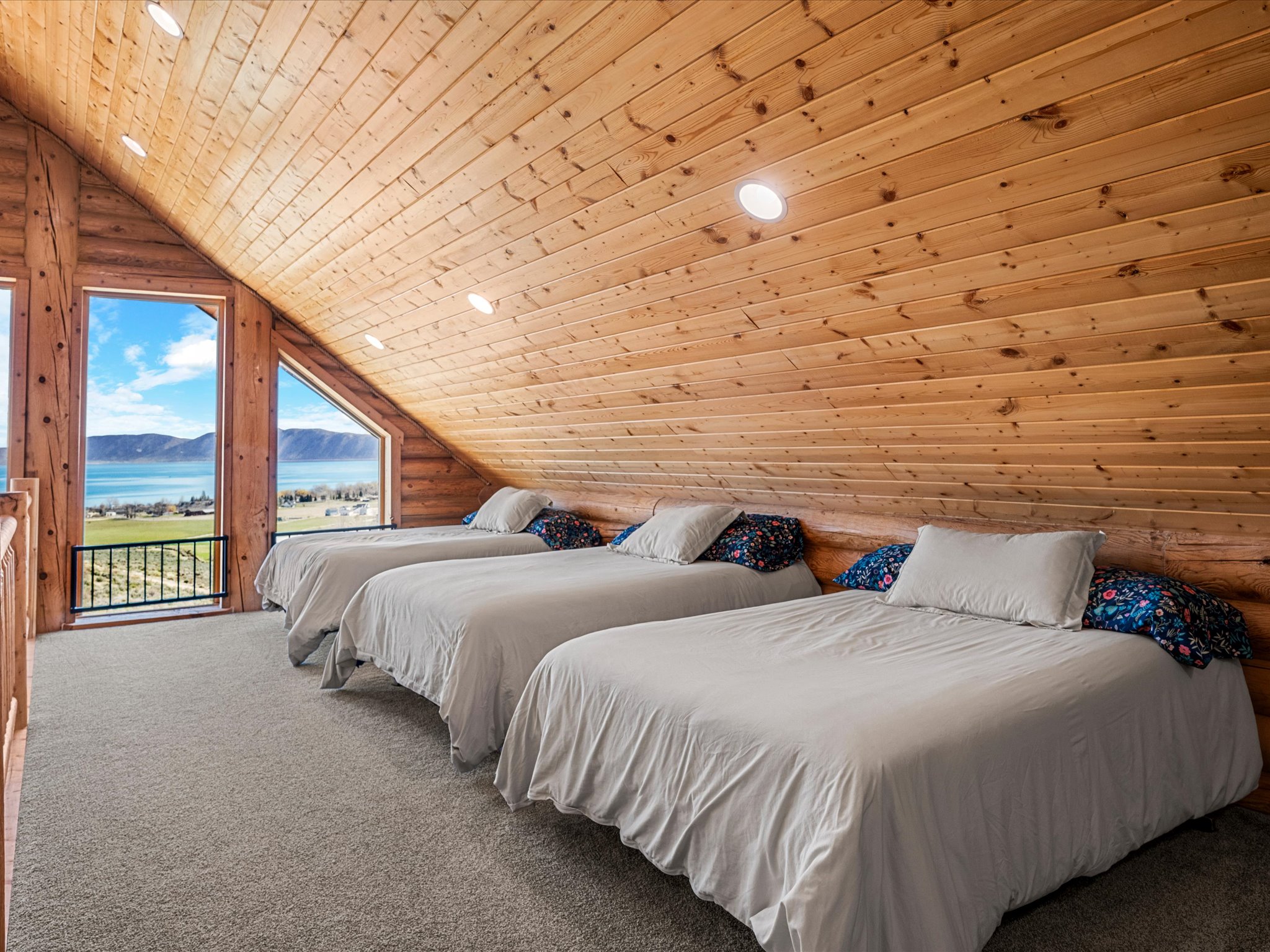 Carpeted room with log walls, a vaulted wood ceiling, recessed lighting, and a water and mountain view
