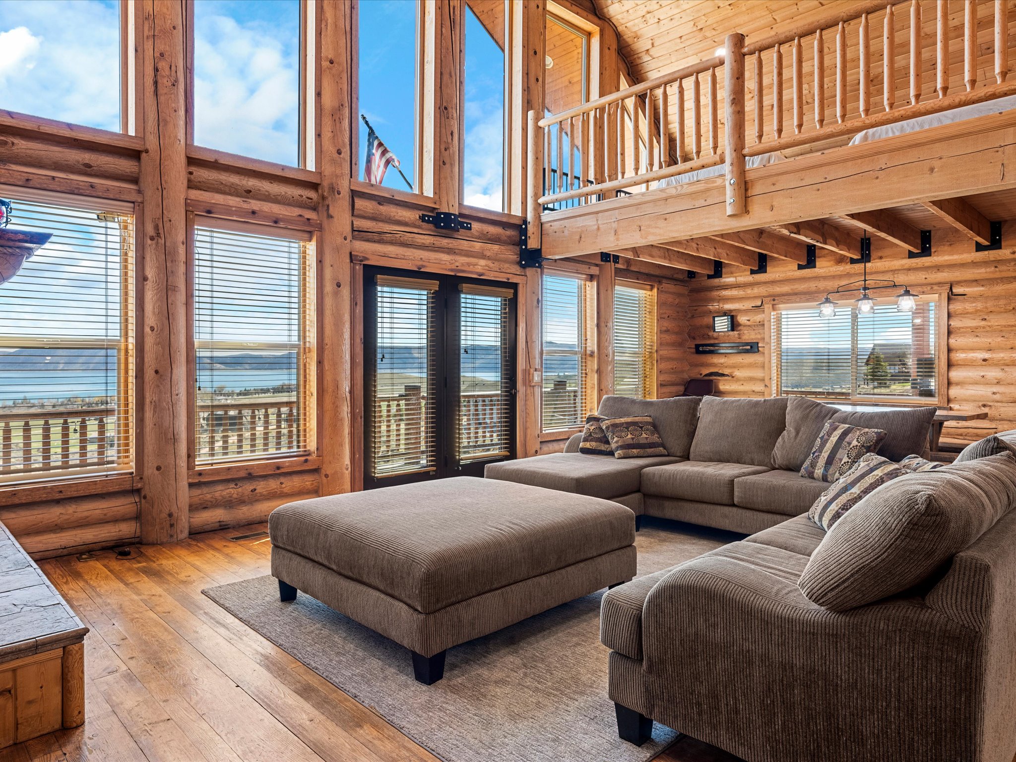 Living area with rustic walls, hardwood / wood-style floors, a water view, and a high wood ceiling