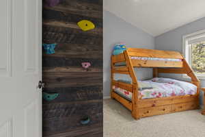 Bedroom with light carpet and lofted ceiling