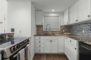 Kitchen featuring stainless steel electric range, dark stone counters, white cabinetry, black dishwasher, and dark wood-style floors