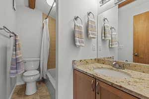 Full bath with vanity, shower / bath combo, and light tile patterned floors
