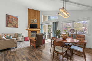 Dining space featuring dark wood-type flooring, a high ceiling, and a large fireplace