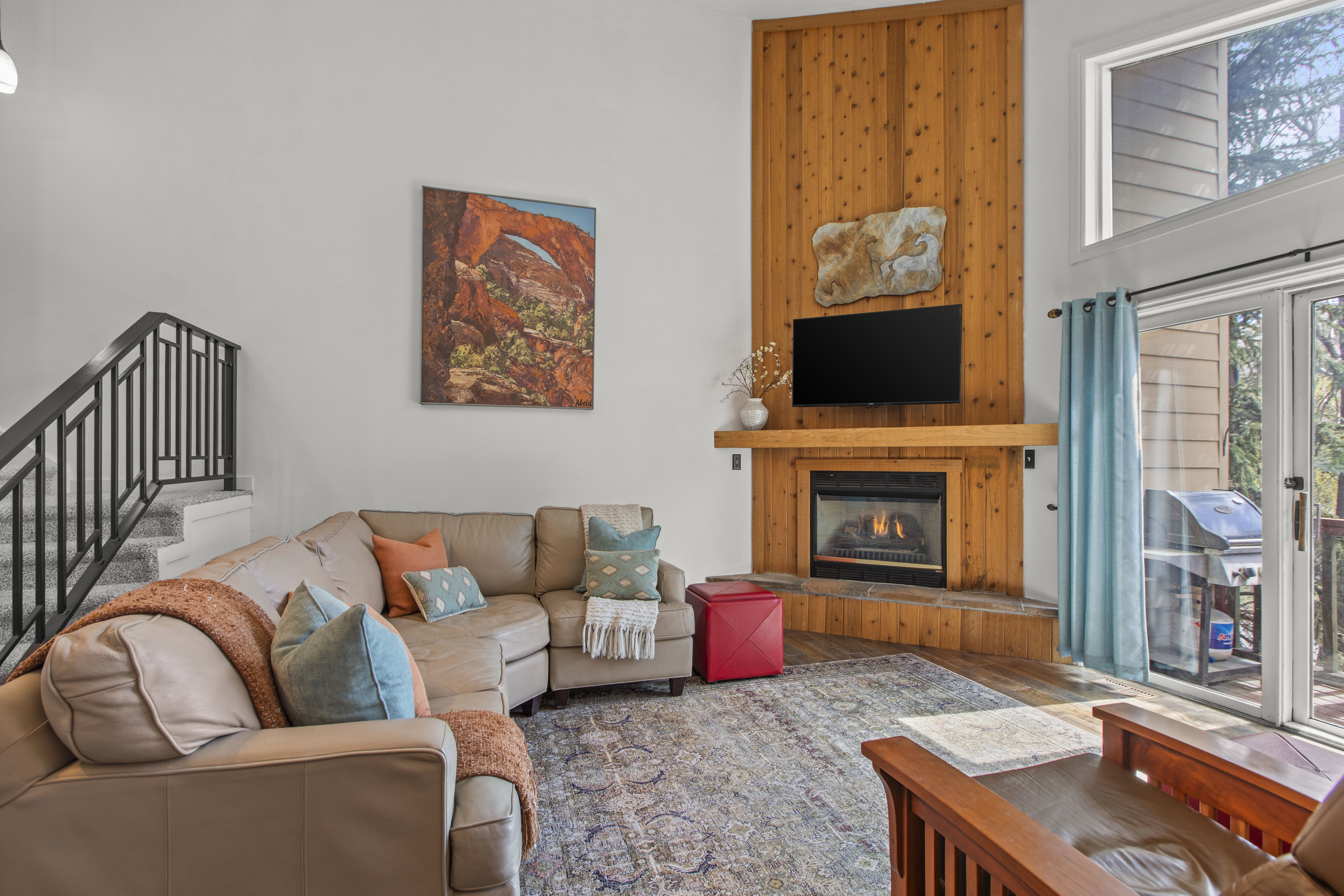 Living area with a high ceiling, wood finished floors, and a glass covered fireplace