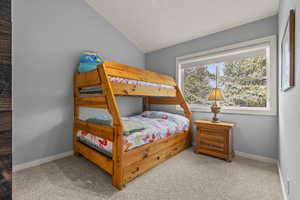 Bedroom with light carpet and vaulted ceiling