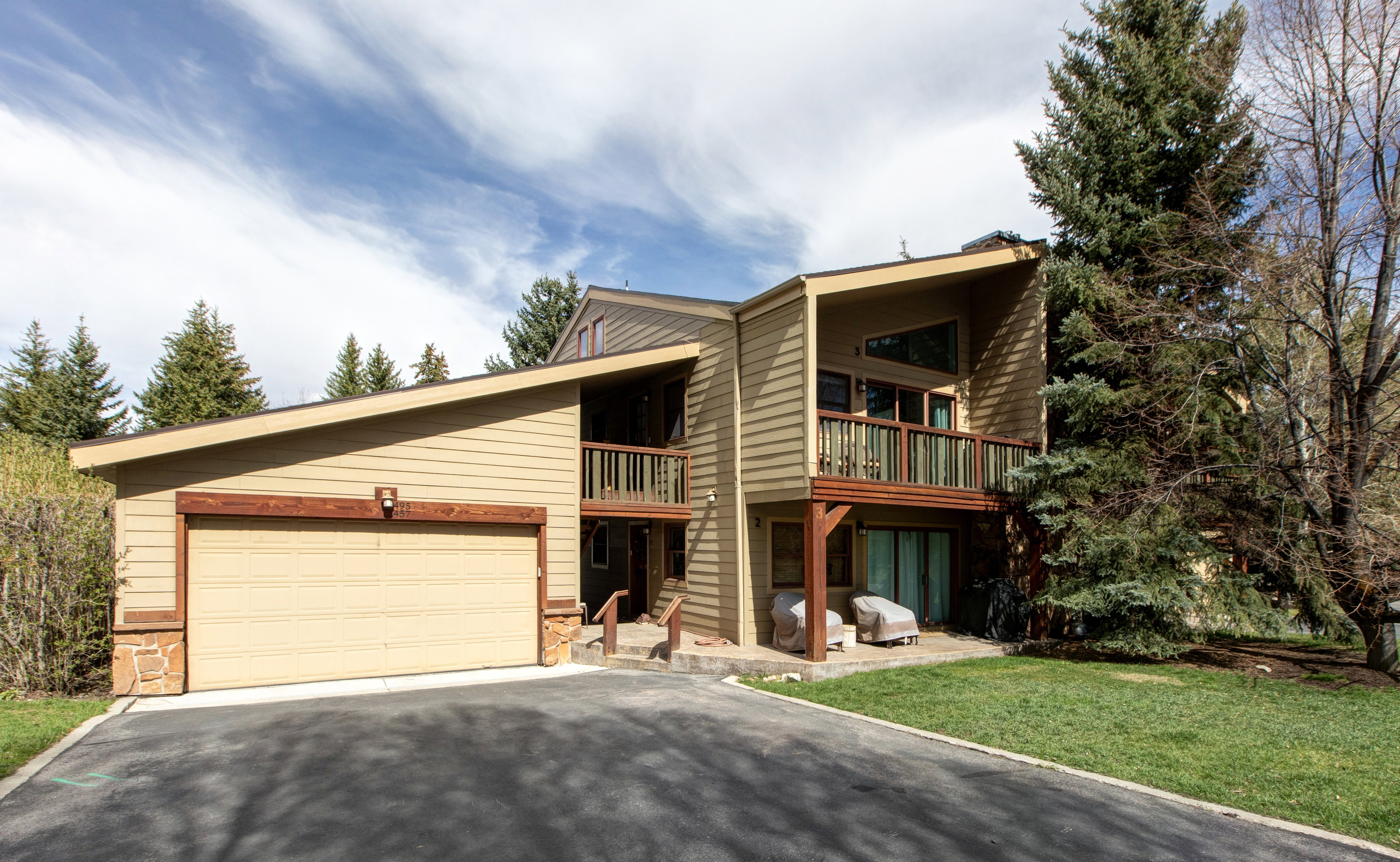 Mid-century modern home with driveway, a balcony, a front lawn, and an attached garage