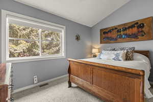 Bedroom with vaulted ceiling and light carpet